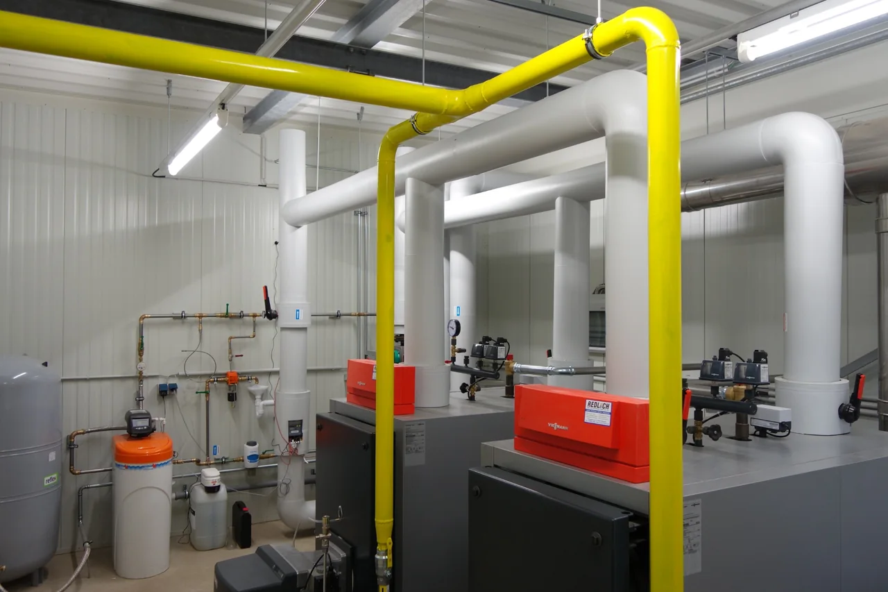 Gaskessel mit gelber Gasleitung und gedämmten Rohrleitungen in einer Wärmezentrale